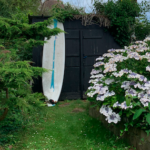 Planche de surf dans un jardin à Pourville-sur-Mer en Normandie, ambiance maison de bord de mer