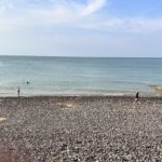 Baignade en famille sur la plage de Pourville-sur-Mer en été, galets et mer calme de la Manche