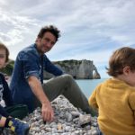 Famille avec deux enfants sur la plage de galets à Étretat face aux falaises