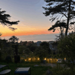Vue sur la mer au coucher du soleil depuis un jardin de gîte à Pourville-sur-Mer avec lumières extérieures