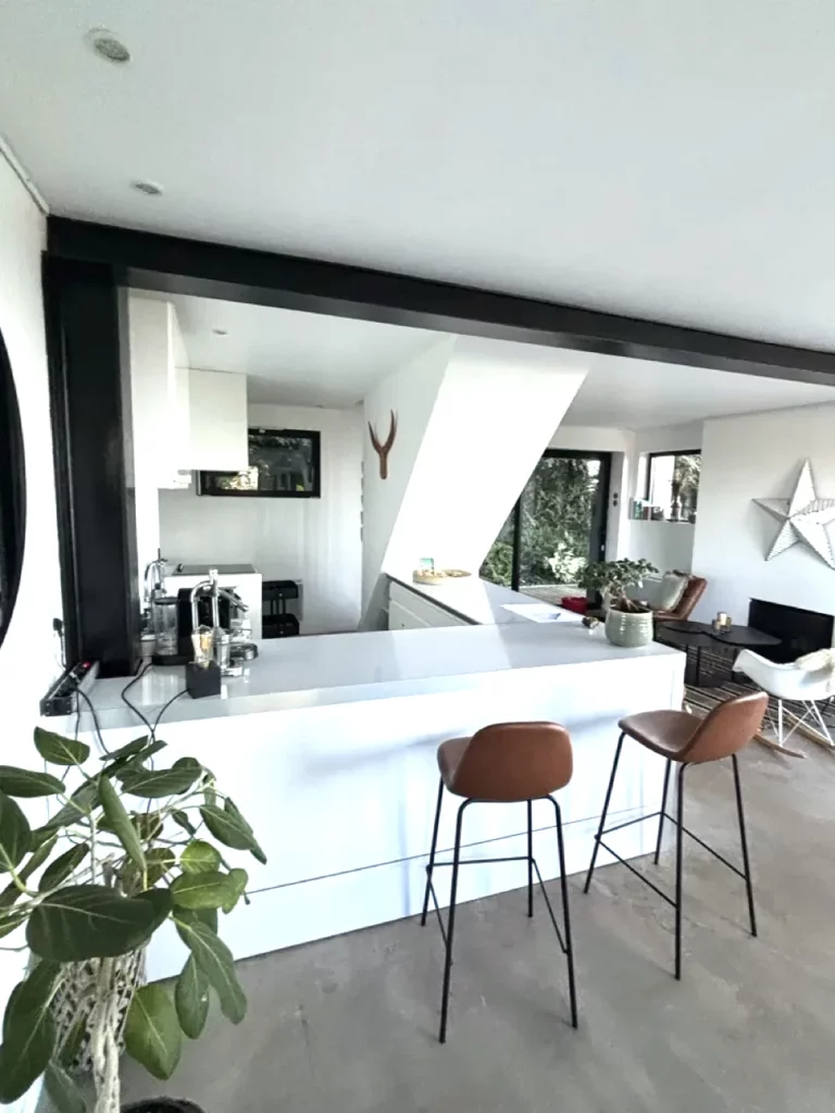 Weiße Bar der offenen Küche mit cognacfarbenen Hockern und Blick ins Wohnzimmer