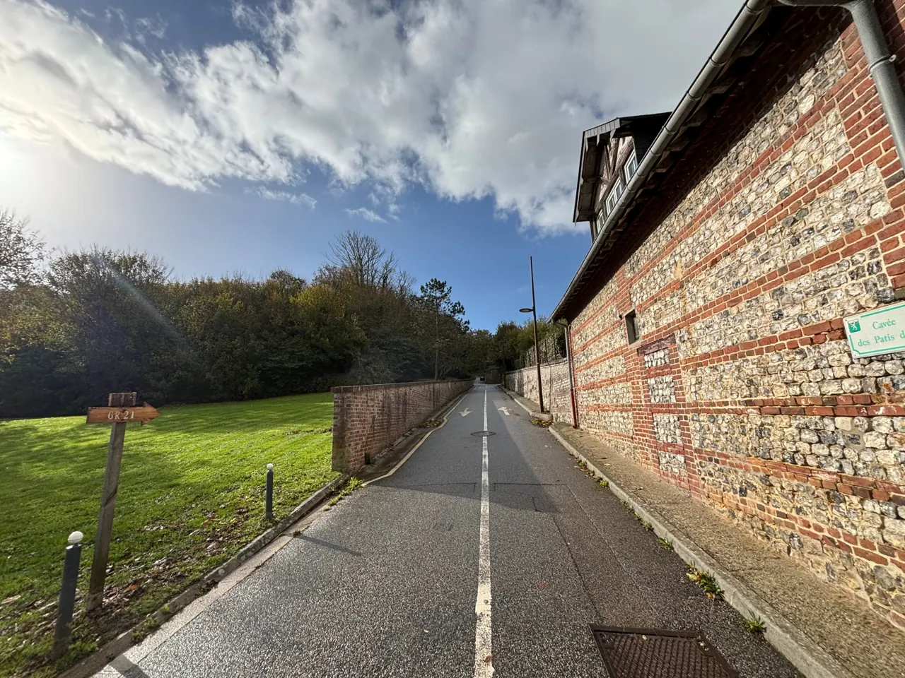 Cavée des Patis et GR21 Mur traditionnel en silex et brique et panneau de rue à Pourville-sur-Mer, près du GR21