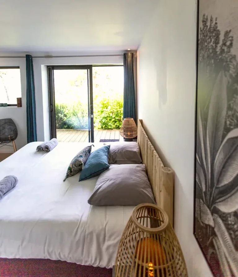 Zimmer Albion im Erdgeschoss mit Doppelbett, Holzkopfteil und Fensterfront zum Garten