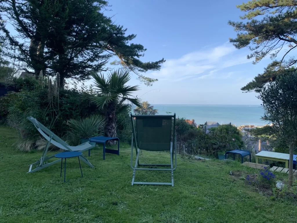 Chiliennes sur la pelouse du jardin, palmier et mer bleue au loin, à Pourville-sur-Mer