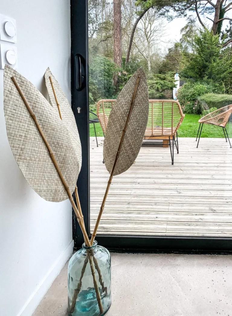 Geflochtene getrocknete Blätter in einer Glasvase vor der Fensterfront zur Terrasse des Carré Vue Mer