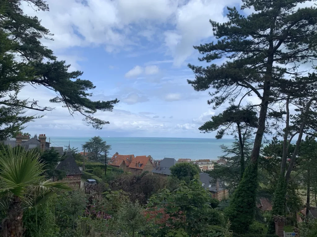 Blick aufs Meer zwischen den hohen Kiefern über den Dächern von Pourville-sur-Mer